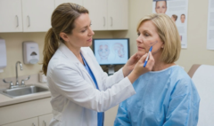 doctor examining and marking face for facelift and cheek lift