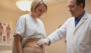 doctor checking patients abdomen