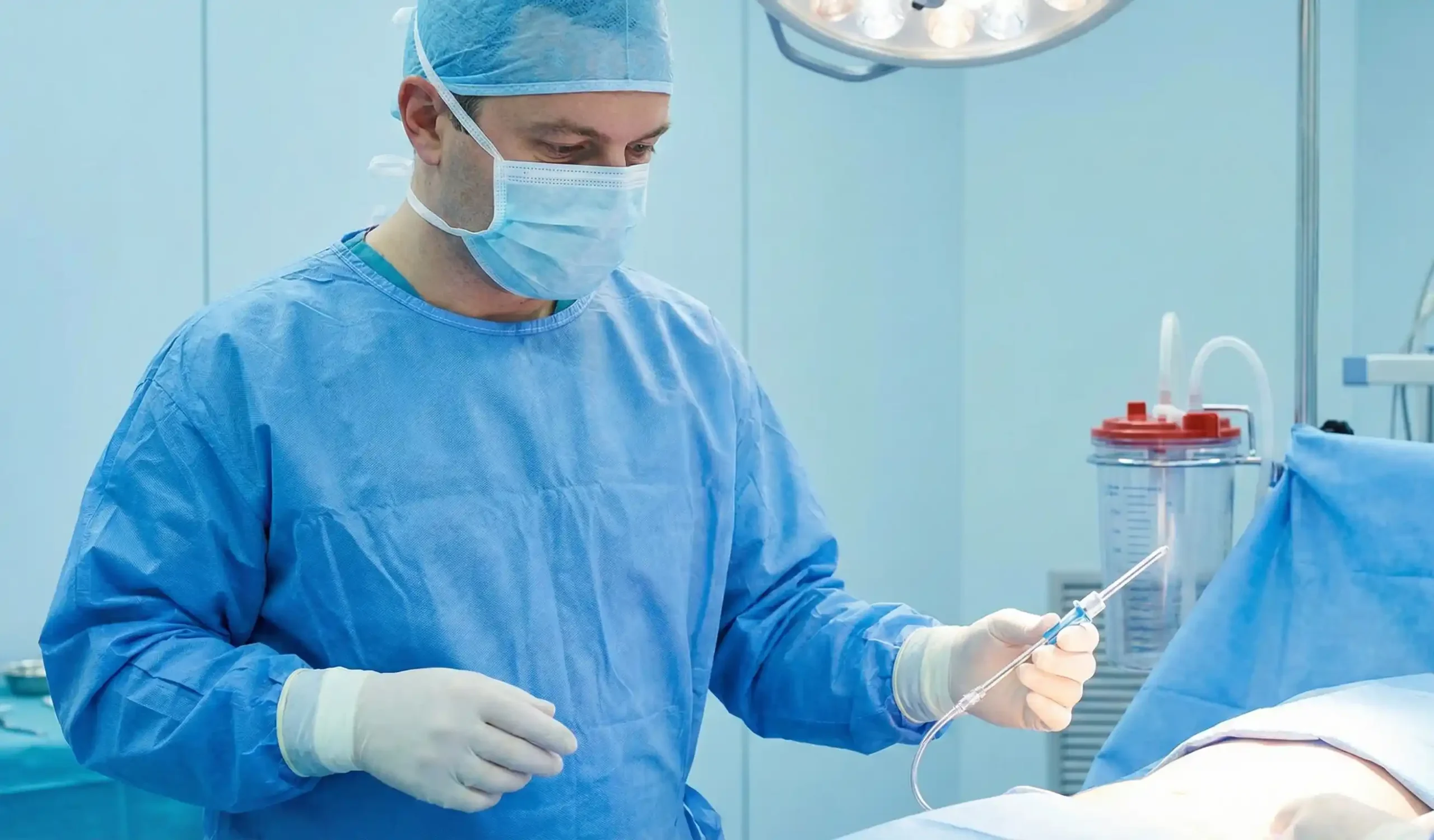 liposuction surgeon in operating room holding cannula